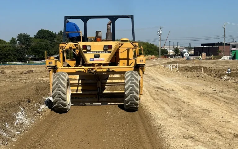 Caterpillar compactor smoothing dirt on a construction site.